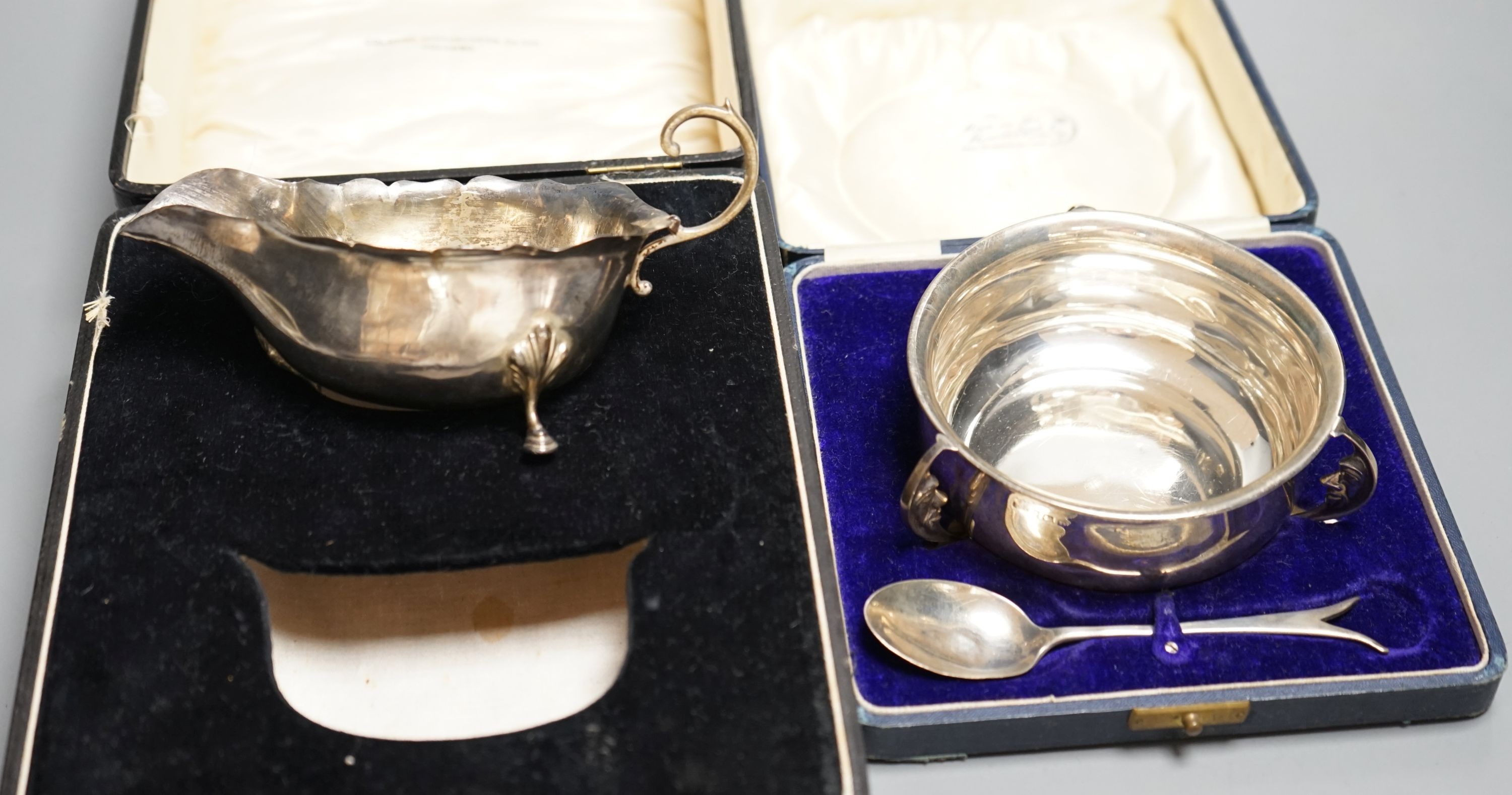 A cased George V silver three handle bowl and spoon, Birmingham, 1928 and a silver sauceboat, 7oz.